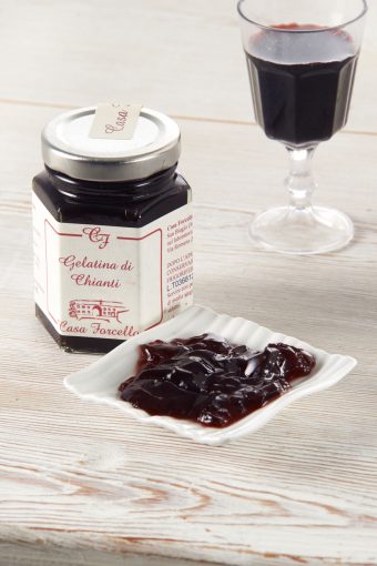 Chianti wine jelly in a small dish with a glass of chianti beside it